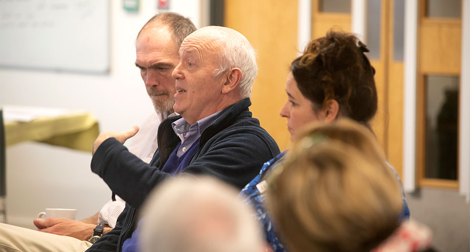 Older man speaking within a seated group